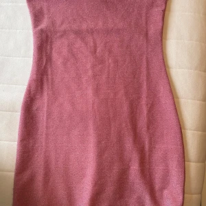 rosa & glittrig strapless miniklänning - kort, rosa klänning i glittrigt material från h&m divided. tight i passformen, men stretchigt material. klänningen är lite ljusare rosa än på de första två bilderna, ungefär samma rosa som på den tredje bilden där etiketten visas. några tecken på användning som visas på de sista två bilderna.