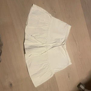 Vit kortkjol med volang och knytband - En jättesnygg off-white kjol från Brandy Melville som är i mycket bra skick. Dock är lappen bortklipp då den var oskön. Den passar med allt och är perfekt för sommaren 🌸Den är i onesize men skulle säga att den passar som en S. Skriv om ni har några frågor eller vill ha flera bilder!💕