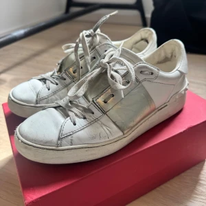Vita sneakers från Valentino med silverdetaljer - Säljer ett par vita och silverfärgade Valentino sneakers. De är slitsamt använda men fungerar hur bra som helst. Tillkommer het nya skosnören, en låda och även en dustbag!