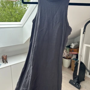 Svart ärmlös klänning från H&M Divided - En enkel svart ärmlös klänning från H&M Divided. Modellen är rak och har rund halsringning. Perfekt för varma dagar eller att styla med en jacka. Tillverkad i mjuk bomull för en bekväm känsla.