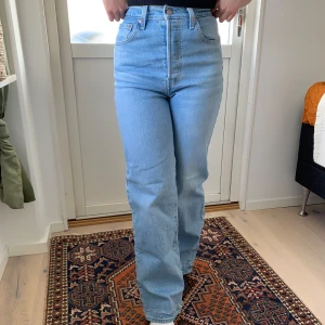 Levi’s ribcage straight ljusblå jeans - Ljusblå Levi’s ribcage straight jeans med hög midja och raka ben. Klassisk femficksmodell med knappgylf. Fransig detalj i benslut för en avslappnad look. Säljer på grund av att de är lite för långa för mig. Använd ett fåtal gånger. Storlek: W25 L34. Nypris 1349kr. https://carlings.com/sv/p/levis-ribcage-straight-ankle-ljusbla-jeans-byxor-jeans-dam/7368638_F522