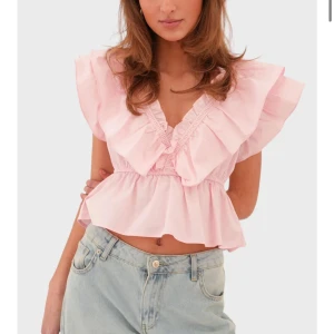 Ljusrosa volangblus med v-ringning - Supersöt ljusrosa blus med volanger och djup v-ringning. Croppad modell med korta, vida ärmar och rynkade detaljer. Perfekt att styla med jeans för en trendig look. Är i storlek S/M, stor i bysten. Ifrån Meet me there i nyskick med prislapp kvar! 💞