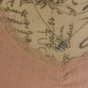 Ljusrosa långärmad topp med spets från Lindex - Söt ljusrosa långärmad topp från Lindex med v-ringning och spetskant. Toppen har små hålmönster och är ribbad i materialet, vilket ger en fin struktur. Perfekt för dig som gillar en feminin och enkel stil.