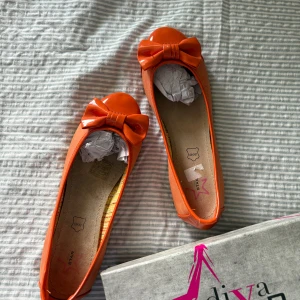 Orange ballerinaskor med rosett - Sjukt snygga orange ballerinaskor med rosett framtill! Skorna är helt nya och endast provade. Äkta läder. Skorna har ett litet märke på sidan, visas på bild. Skriv vid frågor! 💕
