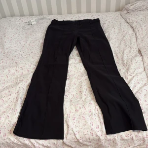 Svarta kostymbyxor med bootcut - Säljer ett par svarta kostymbyxor med bootcut passform. Byxorna har klassisk design med pressveck och normal passning. Perfekta för en stilren look.