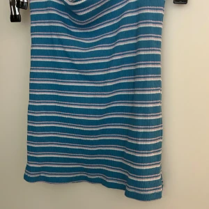 Blå- och vitrandig ribbad topp från MANGO - Blå ribbad topp från MANGO med vita och ljusrosa ränder. Kan användas som både topp och kjol och har en tight passform.