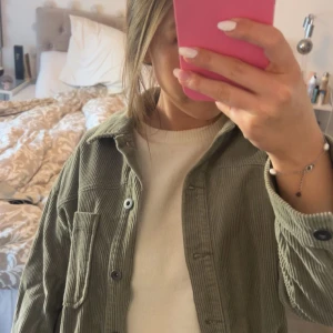 Grön manchester jacka ZARA - Säljer en grön jacka i manchester med klassisk krage och knäppning framtill. Jackan är från Zara och har en bröstficka och svarta knappar. Perfekt att slänga över en t-shirt eller hoodie för en avslappnad look.💗