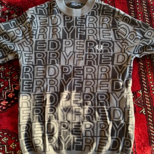 Mönstrad tröja från Fred Perry - Cool tröja från Fred Perry med all-over logomönster i svart och beige. Tröjan har rund halsringning och långa ärmar. Sällsynt mönster o tröja, 