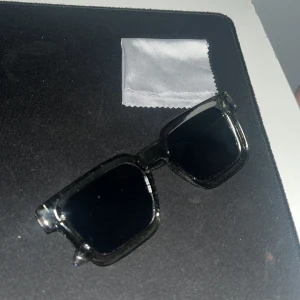 Snygga solglajor, sköna och snygga till sommaren! - Snygga solglasögon med svart, transparent båge och mörka fyrkantiga glas. Perfekt accessoar för soliga dagar. Kommer med putsduk.