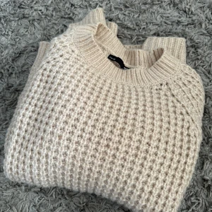 Beige stickad tröja från 157 - Säljer en beige stickad tröja från 157 i storlek XS. Tröjan har ett grovt stickat mönster och rund halsringning med bred ribbad kant. Perfekt för kyliga dagar och enkel att matcha med olika outfits.