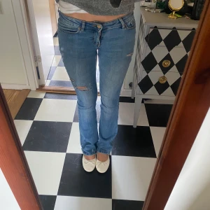 bootcut jeans med hål - Säljer ett par ljusblå bootcut jeans med hål i, de är köpta på Vero Moda för 550kr nypris. De är väldigt lågmidjade och har slitning längst ner på ena benet❤️❤️❤️
