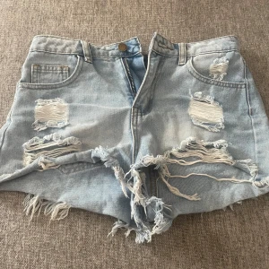 Ljusblåa slitna jeansshorts - Ljusblå jeansshorts med flera slitningar och fransar nertill. Köpte på Plick nydligen men de är för små.