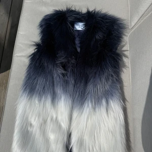 Blå och vit pälsväst från Dondup - Säljer en snygg pälsväst från Dondup i blått och vitt med ombre-effekt. Västen har lång, fluffig fuskpäls och de finns två knäppen på insidan för att stänga den. Storlek 40. Nypris 3000kr