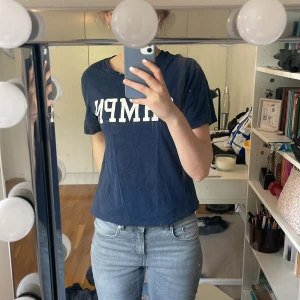 Mörkblå t-shirt med CHMPN-tryck - Säljer en mörkblå t-shirt från CHMPN med vitt tryck framtill. Klassisk rund halsringning och korta ärmar. Perfekt till jeans eller shorts för en avslappnad stil.
