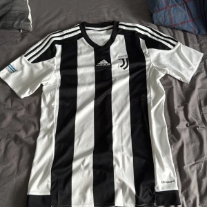 Juventus Academy tröja - Juventus Academy fotbollströja från Adidas med svartvita vertikala ränder, klassiska Adidas-ränder på axlarna och Juventus Academy-tryck på ärmen. Tillverkad i lätt och ventilerande climacool-material. ‼️Inga tillbehör. Sällsynt modell‼️