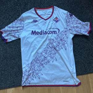 Fiorentina bortatröja 2022/23  - Säljer en vit Fiorentina bortatröja. Perfekt till sommaren och riktigt snygg,Köpt i florence i en äkta Fiorentina butik 