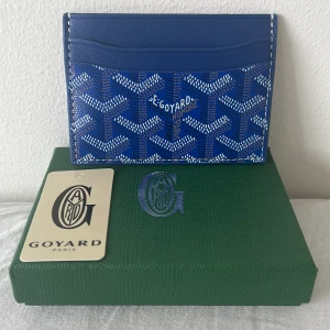 Blå korthållare från Gojard - Snygg blå korthållare från Gojard med mönster i vitt och blått. Korthållaren har massa fack för kort och sedlar. Perfekt accessoar för att lyxa till din stil. PRISET KAN DISKUTERAS.