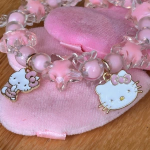 Fint elastiskt armband med Hello Kitty!  - Fint rosa elastiskt armband med rosa pärlor och Hello Kitty-berlocker. Nytt!