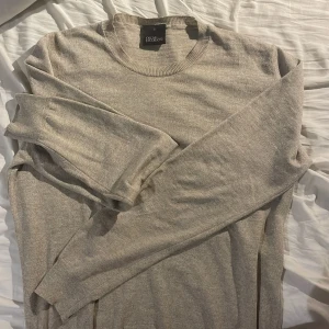 Oscar jacobsson sweatshirt - Säljer en stilren beige tröja från Oscar Jacobson. Tröjan är tunnstickad och har långa ärmar och ribbade muddar vid hals, ärmslut och nederkant. Perfekt med en fet tröja nu till våren. Skriv vid minsta funderingar!