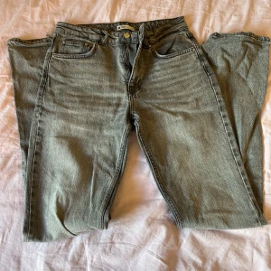 Grå jeans  - Säljer ett par grå jeans från ginatricot med normalhög midja, små slit längst ner på byxorna.