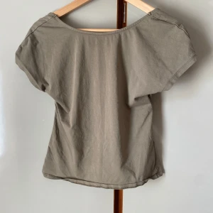 Grön topp med öppen rygg - Säljer en grön topp med korta ärmar och snygg öppen rygg med. Perfekt för dig som gillar stilrena basplagg med en twist. Passar till många olika outfits! Från Nelly och är använd 1 gång. Storlek L men passar M