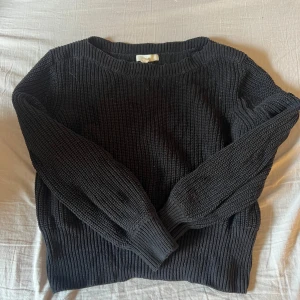 Svart stickad tröja från H&M - Mysig svart stickad tröja från H&M med rund halsringning och långa ärmar. Perfekt för kyligare dagar och enkel att matcha med olika outfits. Klassisk modell med ribbade muddar vid ärmslut och nederkant.