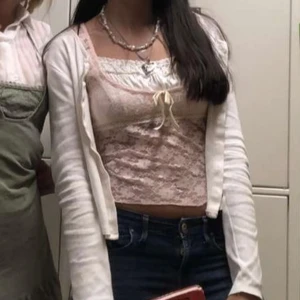 Söt spetsig blommig linnetopp - Romantisk ljusrosa och vit linnetopp i spets med blommigt mönster. Toppen är croppad, har små ärmar och en söt rosett framtill. Perfekt för dig som gillar lite y2k eller coquette och vill ha en feminin vibe. Materialet är mjukt och stretchigt. Den har bleknat lite i färg och är använd många gånger men ser fortfarande fin ut!