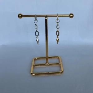 Mixade örhängen i silver och guld - Snygga örhängen med kedjor och spetsiga hängen, ett i silver och ett i guld. De har coola geometriska former och ger en edgy vibe. Perfekta för dig som gillar att mixa metaller och sticka ut lite extra.