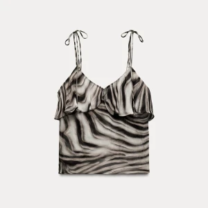 Zebramönstrad linnetopp med volang - Snygg linnetopp med zebramönster i svart och grått. Toppen har tunna axelband med knyt och en volangdetalj längs bysten. Perfekt för dig som vill sticka ut med en trendig och cool look. Axel banden är justerbara och den är en storlek m men passar mig jätte bra som xs. Axelbanden har tecken på slitage eftersom man knyter dom men det är verkligen ingeting som syns när du har på dig den.