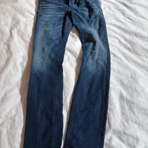 Mörkblå slim fit jeans Jack & Jes - Snygga mörkblå jeans från Jack & Jes i modellen Slim Fit Tim. Jeansen har klassisk femficksdesign, raka ben och diskreta slitningar framtill. Perfekta för dig som gillar en smalare passform och stilren look.
