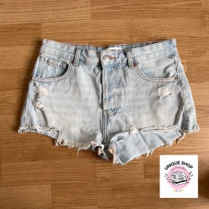 Ljusblåa jeansshorts med slitningar - Snygga ljusblå jeansshorts från FM Pull&Bear med slitna detaljer och fransig kant. Klassisk femficksmodell med knapp och dragkedja framtill. Perfekta för varma dagar och ger en avslappnad vibe. Midje: 38cm rakt över! 🫶🏻