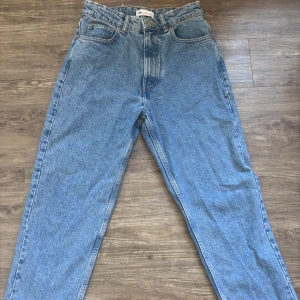 Zara jeans hög midjs - Säljer ett par blå jeans i klassisk denim med raka ben och mom fit . Byxorna har normal passform, midja med hällor och klassiska jeansdetaljer. Perfekta för dig som gillar en avslappnad och cool stil
