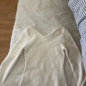 Vit stickad tröja med v-ringning - Säljer en vit stickad tröja med snygg v-ringad hals och långärmade ärmar. Tröjan har en mjuk och lite grovstickad känsla, den har vida ärmar🩷 använd ca 2 gånger, inga defekter. Den är lite grädd vit