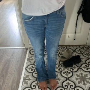 Blå jeans från Gina Tricot, st - Säljer ett par klassiska blå jeans från Gina Tricot i storlek 164. Jeansen har rak passform, normal midja och snygga slitningar framtill. De har fem fickor, dubbla knappar i midjan och är tillverkade i mjukt denimtyg. Perfekta för en chill och stilren look.