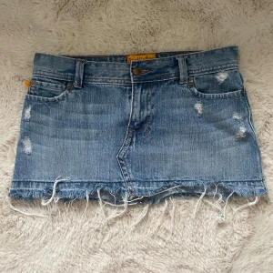 Blå jeanskjol från Hollister - Snygg blå jeanskjol från vintage Hollister med slitna detaljer. I storlek 1 vilket motsvarar/passar storlek XS. Jeanskjolen är i mycket bra skick.
