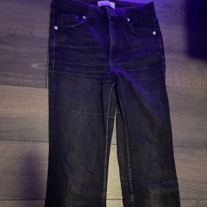 Svarta raka/bootcut jeans - Snygga svarta jeans från Zara. Jeansen har en mörk tvätt och midjehög passform, perfekta till sneakers eller boots. Materialet är slitstarkt och bekvämt, passar till många olika stilar.