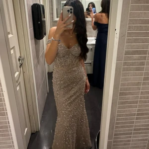 Champagnefärgad glittrig balklänning - De är en balklänning som jag hade i en förlovning. Jätte fin på sitter som den ska. Däremot är den ganska tung pga all små detaljer som sitter på. Är i storleken Xs köp för 4000kr och de kommer med en vale som sitter på midjan av klänningen