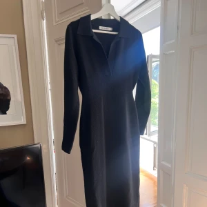 Svart långärmad klänning från Adoore - Stilren och snygg svart långklänning från Adoore med krage och v-ringning. Figursydd passform. Passar alla tillfällen 🖤