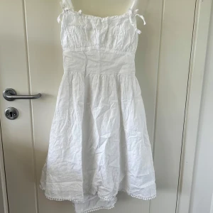 Vit kort klänning från Gina Tricot - Superfin vit kort klänning från Gina Tricot med broderade små blommor, knytning fram och smala axelband 🤍 Använd en gång vid konfirmation🤍 Säljs på grund av att den blivit för liten🤍 normal i storlek