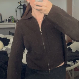 Brun stickad jacka från Å Woman XS - Mörkbrun stickad jacka från Å Woman i storlek XS. Jackan har dragkedja framtill, klassisk krage och långärmad passform. Perfekt för dig som gillar en clean och enkel look med en touch av retrovibe. 600kr nypris, och den är aldrig använd 