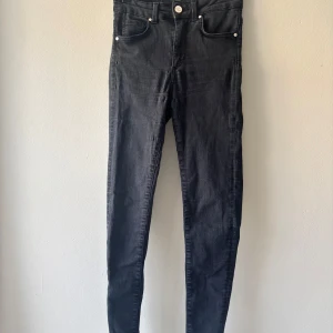 Svarta skinny jeans från Never Denim - Svarta jeans, lite nötta mellan benen men fortfarande mycket kvar att ge.   Passar någon som är mellan 157-165cm skulle jag tro.  Från sida till sida vid byxöppning: 33cm