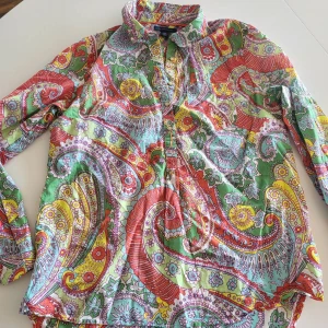 Färgglad blommig skjorta Tommy Hilfiger - Säljer en superfärgglad skjorta från Tommy Hilfiger i storlek M. Skjortan har ett blommigt och paisley-inspirerat mönster i grönt, rött, gult, lila och turkost. Långärmad med klassisk krage och knappar framtill. Perfekt för dig som gillar att sticka ut med din stil!