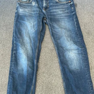  blå jeans straight fit -  jeans i blå tvätt med snyggt slitna detaljer och raka ben. Jeansen har fem fickor, knappgylf och kontrastsömmar. Perfekta för en avslappnad och tidlös look.