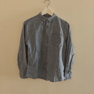 Zara skjorta - Snygg blå skjorta från Zara Kids i storlek 164. Skjortan har klassisk krage, bröstficka och knäppning framtill. Tillverkad i mjuk bomullsmix med viskos för extra komfort. Perfekt till jeans eller chinos för en clean look.