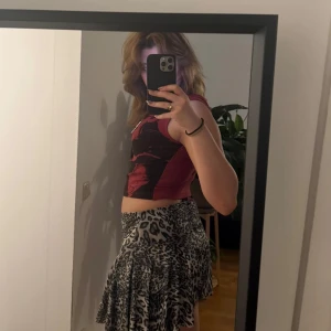 Röd ärmlös topp från Minga London - Säljer en cool röd ärmlös topp från Minga London med ett unikt tryck i svart. Perfekt för att ge din outfit en edgy touch. 