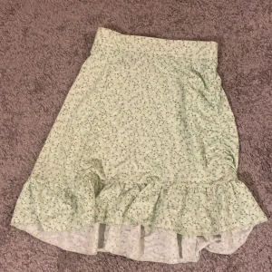 Kjol storlek xs - En grön kjol med blommor på andvänd några gånger med de syns inte