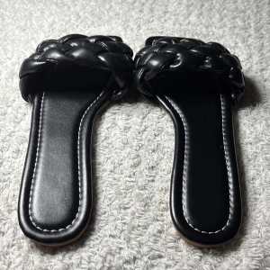 Svarta flätade sandaler med fyrkantig tå - Stilrena svarta sandaler med bred, flätad rem över foten och trendig fyrkantig tå. Tillverkade i syntetmaterial med mjuk känsla och kontrastsömmar längs sulan. Liten i storleken men perfekta för en chill sommarlook eller när du vill ha något enkelt men snyggt. 