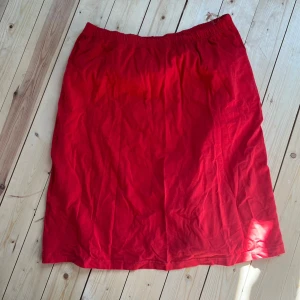 Röd långkjol med resårmidja - Enkel och snygg röd långkjol med resår i midjan. Kjolen är rak i modellen och gjord i ett mjukt bomullstyg som känns skönt mot huden. Perfekt för dig som vill ha en färgstark och bekväm kjol till sommaren.