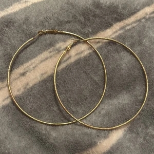 Stora guldiga hoops örhängen - Säljer ett par stora, tunna hoops i guldig färg. De är runda och har en enkel, stilren design som passar perfekt om du vill sticka ut lite extra. Lätta att bära och stängs med klassiskt lås. Perfekta för att lyfta vilken outfit som helst.