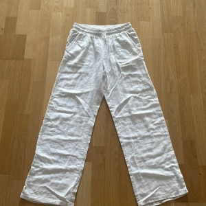 Vita linnebyxor från Lindex, stl 152 - Snygga och luftiga vita linnebyxor från Lindex med resår i midjan och raka, vida ben. Perfekta för varma dagar och chill stil. Byxorna har fickor på sidorna och är tillverkade i ett skönt linnematerial.